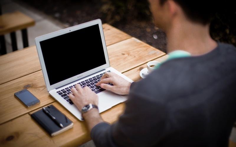 Hands typing on a laptop at a wooden desk